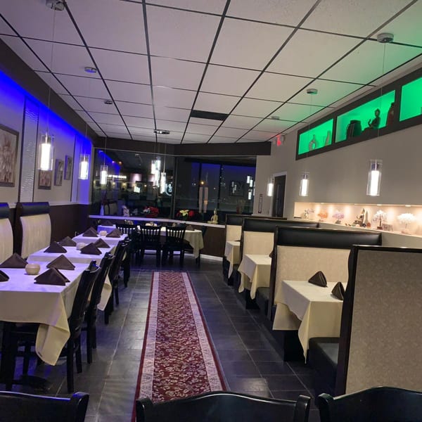 CURRY ZONE's dining room with tables set, blue and green accent lighting, and decorative shelves.