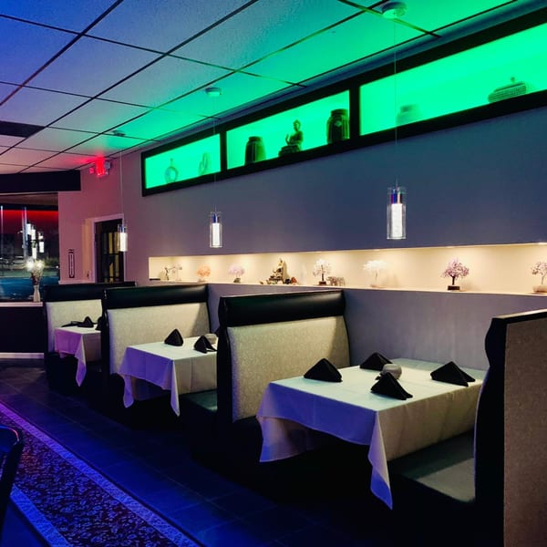 The CURRY ZONE dining room features booths, white tablecloths, and green accent lighting with decorative objects.
