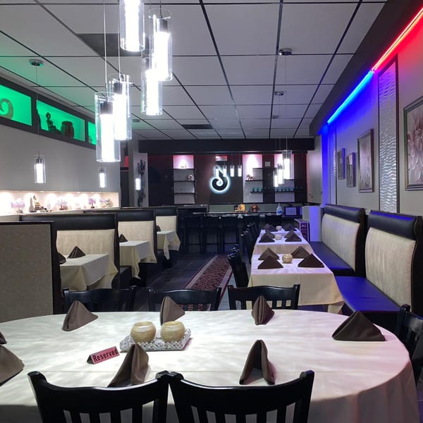 Interior of CURRY ZONE restaurant with tables, booths, and a bar area, featuring modern lighting and decor.